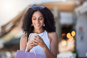 Image showing Black woman, phone reading and shopping bag of a customer on a online shop app for discount. Retail store promotion, urban and mobile networking of a female on a city street with blurred background