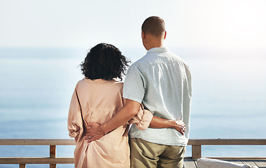 Image showing Back, view and senior couple by beach, hug and enjoying quality time on holiday or vacation. Love, care and retired elderly man and woman hugging, embrace or cuddle while having fun by ocean or sea.