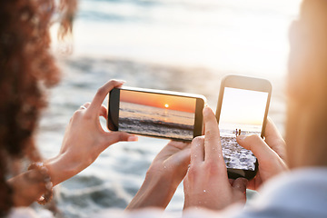 Image showing Phones, beach and couple taking a picture of the sunset while on summer vacation or weekend trip. Technology, adventure and hands of man and woman with cellphones taking photo by the ocean on holiday