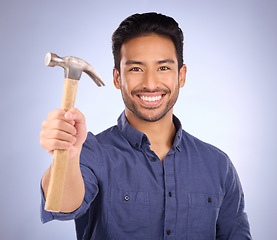 Image showing Construction, showing and portrait of an Asian man with a hammer isolated on a studio background. Building, happy and builder with a tool for repairs, maintenance and handyman work on a backdrop