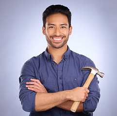 Image showing Man, studio and portrait with tools or hammer for handyman, maintenance or repair work with smile. Happy asian model person on purple background arms crossed for engineer, mechanic or technician job