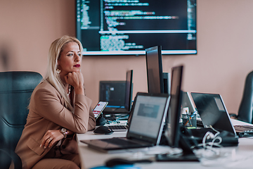 Image showing A businesswoman sitting in a programmer's office surrounded by computers, showing her expertise and dedication to technology.