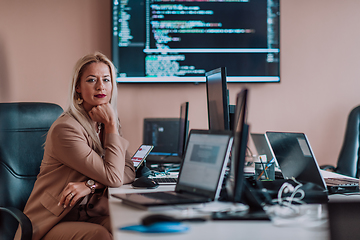 Image showing A businesswoman sitting in a programmer's office surrounded by computers, showing her expertise and dedication to technology.