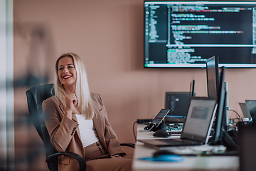 Image showing A businesswoman sitting in a programmer's office surrounded by computers, showing her expertise and dedication to technology.