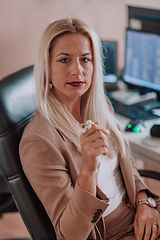 Image showing A businesswoman sitting in a programmer's office surrounded by computers, showing her expertise and dedication to technology.