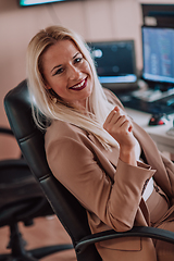 Image showing A businesswoman sitting in a programmer's office surrounded by computers, showing her expertise and dedication to technology.