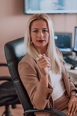 Image showing A businesswoman sitting in a programmer's office surrounded by computers, showing her expertise and dedication to technology.