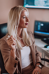 Image showing A businesswoman sitting in a programmer's office surrounded by computers, showing her expertise and dedication to technology.