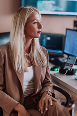 Image showing A businesswoman sitting in a programmer's office surrounded by computers, showing her expertise and dedication to technology.