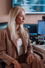 Image showing A businesswoman sitting in a programmer's office surrounded by computers, showing her expertise and dedication to technology.