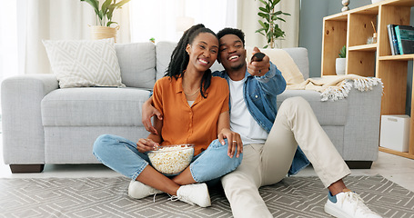 Image showing Happy black couple, eating popcorn and a movie playing in the living room of their home or house. Love, romance and man and woman having leisure time while looking at tv and browsing channels.