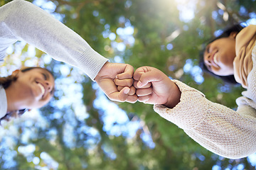 Image showing Fist bump, below and women friends agreement, celebrate greeting of success in partnership with goals outdoor in a park. Low angel, teamwork and happy and excited people on a mission in solidarity