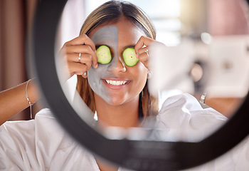 Image showing Woman, vlogger and ring light of skincare influencer holding cucumber on eyes for facial wellness at home. Happy female with beauty face mask smiling for online vlog, social media post or streaming