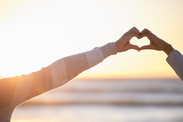 Image showing Couple, heart and hands at sunset for love at beach, date and holiday mockup together. Man, woman and finger shape for care in relationship, support and trust at ocean, hope and freedom of emoji sign