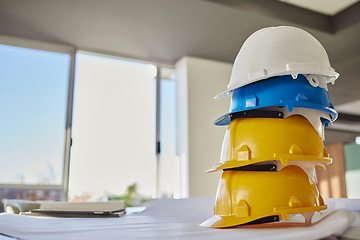 Image showing Building, helmets and architect equipment on table for construction safety, security or industrial work gear at office. Stack of hard hats on desk for safe engineering or contracting for architecture