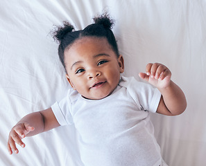 Image showing Above, portrait and baby relax in bed, happy and content after waking up in her home. Face, toddler and girl smile in a bedroom, lying and playing, curious and sweet on a peaceful morning in nursery
