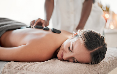 Image showing Woman, hot stones or back massage in spa to relax for zen, meditation or wellness physical therapy treatment in resort. Beauty, salon or happy female for luxury healthcare, rock or spiritual peace