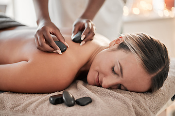 Image showing Woman, hot stone massage and therapist, hands and zen with holistic therapy and spa treatment for back. Calm, peace of mind and face, healing and stress relief with self care at wellness resort