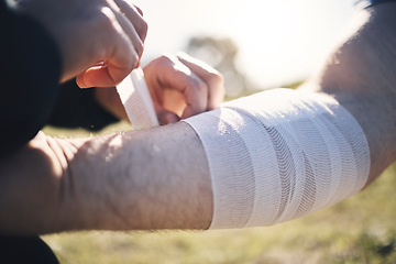 Image showing Hands, arm bandage and first aid after injury, workout or exercise accident outdoors. Medical emergency, help and injured male athlete man with plaster or strap after sports training or exercising.