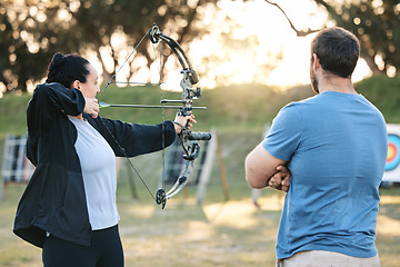 Image showing Archery, sports or help with a woman holding a bow and arrow outdoor for target practice with a coach. Coaching, learning or advice with a female and trainer at the shooting range for weapon training