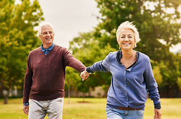 Image showing Old couple holding hands, outdoor in park and smile, happiness with freedom in nature, love and retirement. Happy, man and woman with travel, relationship with trust in marriage and commitment