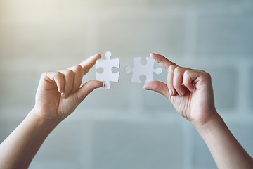 Image showing Hands, puzzle and synergy with a business woman in the office against a brick wall for building or connection. Idea, innovation and strategy with a female employee holding jigsaw pieces at work