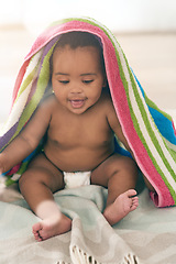 Image showing African baby, girl and sitting for smile with blanket, young or healthy in bedroom at family home. Black infant, toddler and bed with towel for growth, care and health in morning sunshine at house