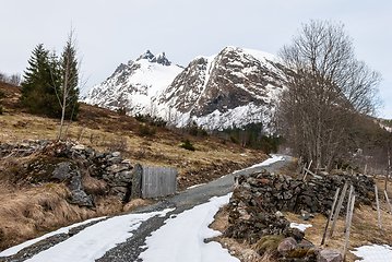 Image showing Stone yard with fence over halfway snow-covered mountain road