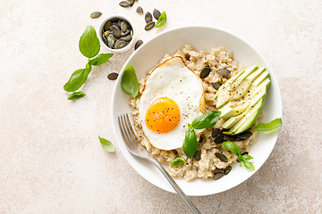 Image showing Savory oatmeal with fried sunny side up egg, avocado and pumpkin seeds for healthy breakfast