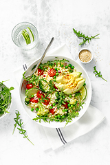 Image showing Couscous salad with broccoli, green peas, tomatoes, avocado and fresh arugula. Healthy natural plant based vegetarian food for lunch, israeli cuisine, top view