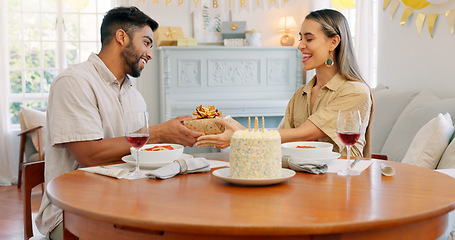 Image showing Interracial, couple and celebrate for birthday with gift, being happy and relax together at party. Romance, man and woman with present, bonding and smile in home in living room for hug or celebration
