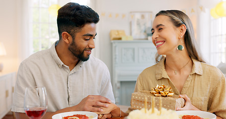 Image showing Interracial couple, gift and celebrate birthday being happy, kiss and smile in home at table with cake. Love, man and woman being content, romantic and present being cheerful celebration together.