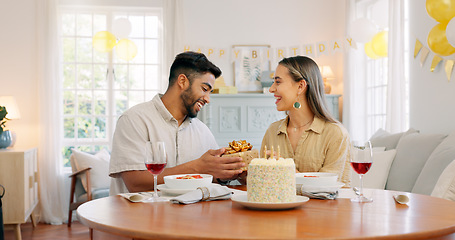 Image showing Interracial, couple and celebrate for birthday with gift, being happy and relax together at party. Romance, man and woman with present, bonding and smile in home in living room for hug and embrace.