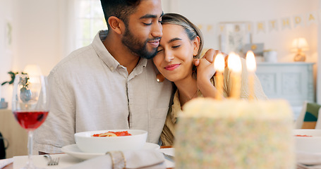 Image showing Interracial couple, gift and celebrate birthday being happy, kiss and smile in home at table with cake. Love, man and woman being content, romantic and present being cheerful celebration together.