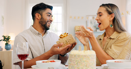 Image showing Interracial, couple and celebrate for birthday with gift, being happy and relax together at party. Romance, man and woman with present, bonding and smile in home in living room for hug and embrace.