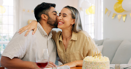 Image showing Interracial couple, gift and celebrate birthday being happy, kiss and smile in home at table with cake. Love, man and woman being content, romantic and present being cheerful celebration together.