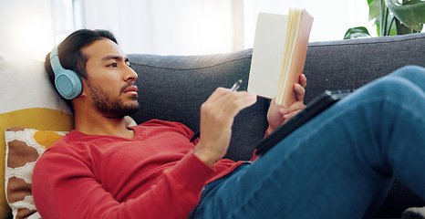 Image showing Finance budget, music headphones and man writing schedule in book, thinking of savings idea and banking on home sofa. Asian person streaming the radio and working on money planning in notebook