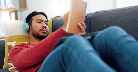 Image showing Writing notes, elearning and student with a mobile listening to music or a podcast while studying. Man working with a notebook and digital tablet while relaxing on a sofa in the living room at home.