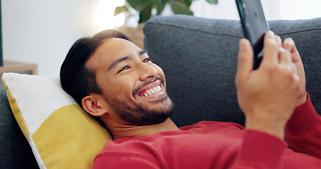 Image showing Sofa, happy and relax man with phone scroll, browse or search social media app for comedy or funny meme. Person lounge on living room couch with happiness, mobile smartphone and reading online comic