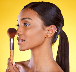 Image showing Beauty, makeup and brush with indian woman in studio for cosmetics, foundation or product. Cosmetology, application and glow with girl model for self care, powder and tool in yellow background studio