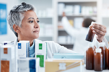 Image showing Senior woman, doctor and medicine for healthcare prescription checking stock on shelf in pharmacy. Elderly female pharmacist holding bottle of medication for inspection at drug store or retail clinic