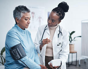 Image showing Black woman, doctor and senior patient with blood pressure reading for wellness, advice and conversation. Medic, elderly client and medical tools for health, cardiology and results in hospital office