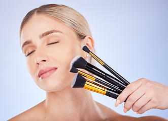 Image showing Eyes closed, face and makeup of woman with brushes in studio isolated on a blue background. Facial cosmetics, beauty skincare and female model with tools to apply foundation or powder for aesthetics.