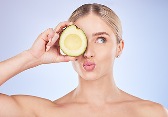 Image showing Face, skincare and woman with avocado in studio isolated on a blue background. Cosmetics kiss, fruit and thinking female model with food for omega 3, nutrition or diet, healthy skin or beauty pout.