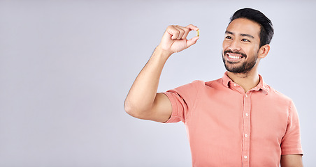 Image showing Young man, supplement pill and smile by studio mockup space for health, self care or wellness. Gen z model, student and medicine for nutrition, diet or omega 3 for healthy brain, mindset and happy