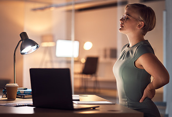 Image showing Woman, office and night for back pain injury, burnout or stress at desk for overtime, fatigue or tired. Young corporate worker, manager and muscle strain in dark workplace, frustrated and stretching