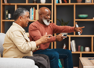 Image showing Gaming, pointing and senior black man friends playing a video game together in the living room of a home. Sofa, funny or retirement with a mature male gamer and friend enjoying a house visit to game