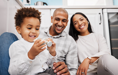 Image showing Black family, children and a boy playing with a toy car while his parents smile, sitting on the kitchen floor. Kids, toys or love with a mother and father watching their male child have fun in a home