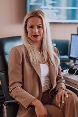 Image showing A businesswoman sitting in a programmer's office surrounded by computers, showing her expertise and dedication to technology.