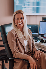 Image showing A businesswoman sitting in a programmer's office surrounded by computers, showing her expertise and dedication to technology.